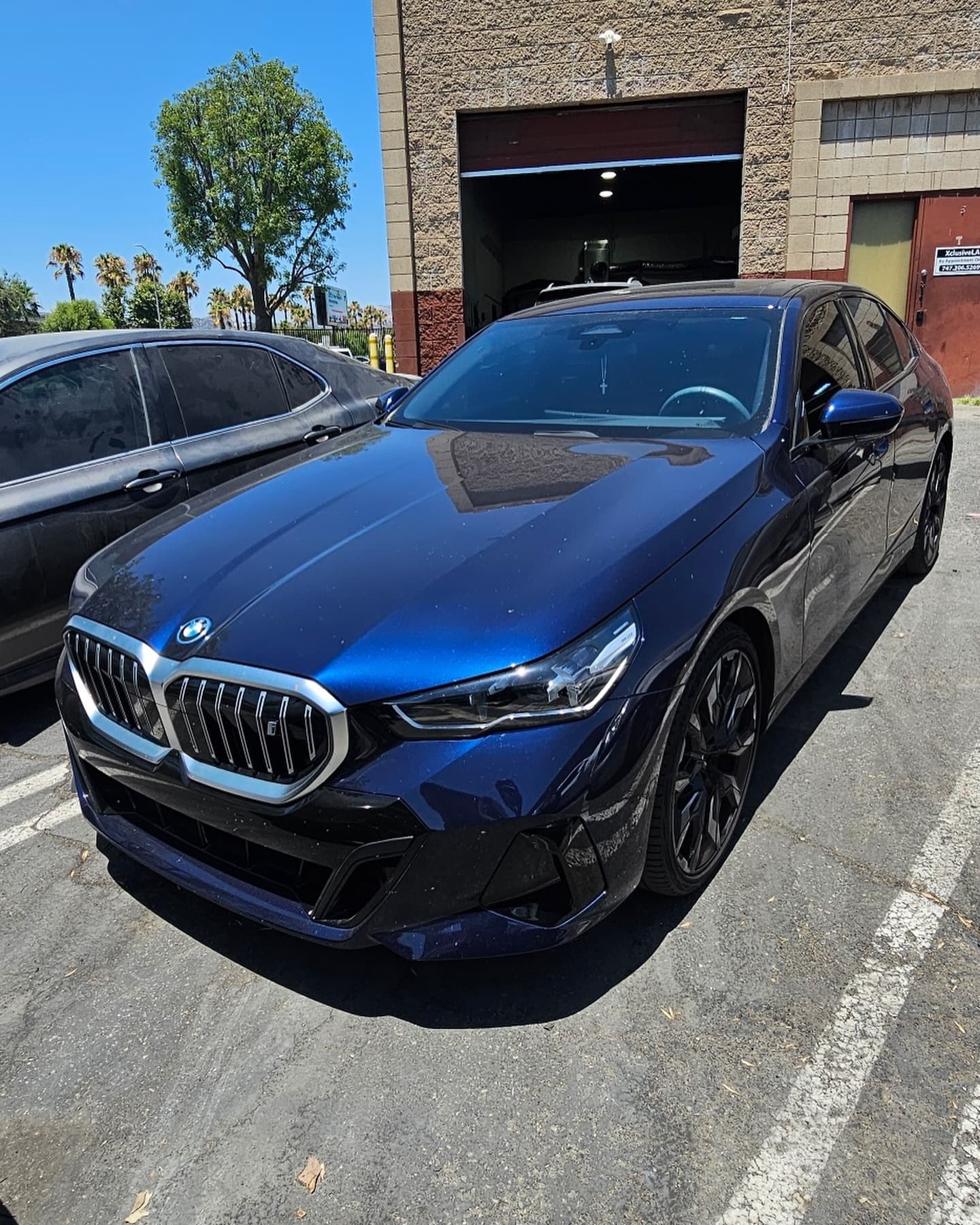 A blue BMW 5-Series parked in front of the shop